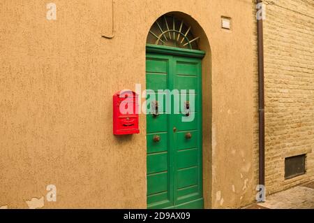 Red mailbox hanging on the wall of a house with a green door ("Lettere" means Letters in the italian language) (Corinaldo, Marche, Italy) Stock Photo
