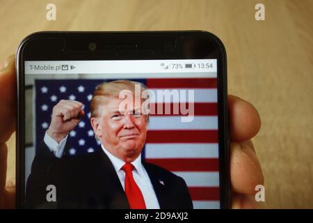 KONSKIE, POLAND - May 18, 2019: hand holding smartphone with photo of Donald Trump with American flag displayed on screen Stock Photo