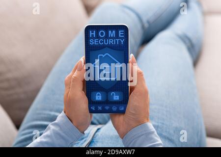 Woman using her smartphone with home security application Stock Photo