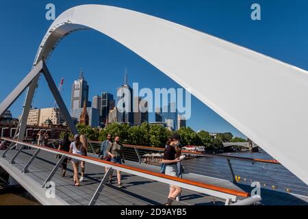 Pedestrians wear masks as they cross over the Yarra river during the coronavirus pandemic. Stock Photo