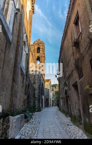 Ancient Rounded Stone An ancient stone wall with a small arch surrounds a Mediterranean ...