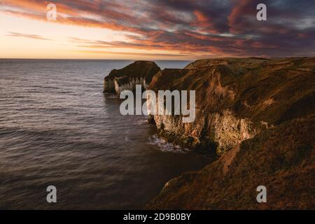 Sunrise over sea and eroded chalk cliffs under bright sky at low tide along north east coastline along Flamborough Head in East Riding of Yorshire, UK. Stock Photo