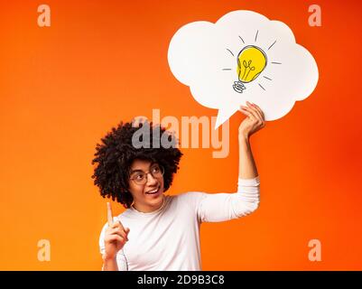 Creative ideas and innovations. African American guy holding speech bubble with light bulb over his head and pointing up Stock Photo