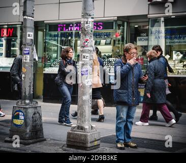 NEW YORK, USA - Apr 27, 2016: Manhattan street scene. Woman with cigarette and mobile phone in the street of New York Stock Photo