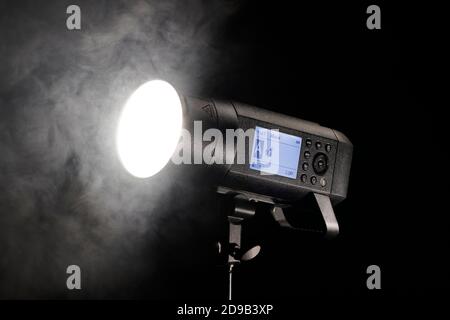 Studio flash light firing on black background with smoke Stock Photo