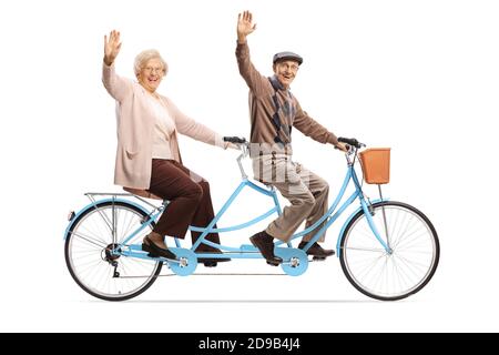 Elderly couple riding a blue tandem bicycle and waving isolated on white background Stock Photo
