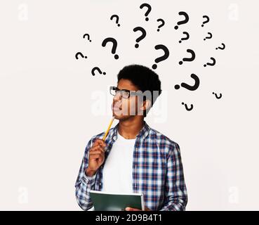 Pensive black man with question marks over his head deep in thought, solving business problem, creative collage Stock Photo