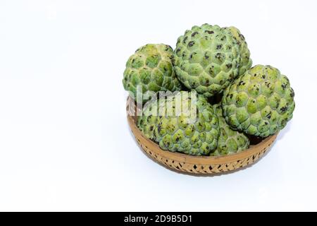 Fresh green Custard apples kept on a wooden basket with white background Stock Photo