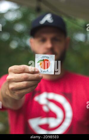 LAWRENCEVILLE, UNITED STATES - Oct 29, 2020: Lawrenceville, GA / United States - October 29 2020: A Georgia voter holds up his 'I Voted' sticker after Stock Photo