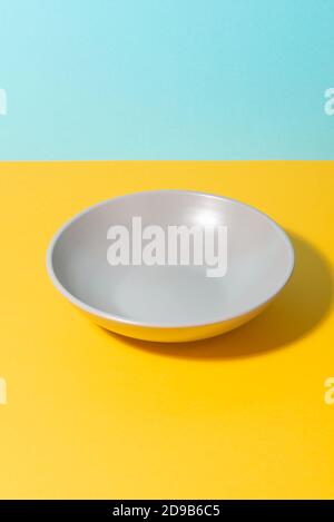 Deep gray plate on yellow and blue background Stock Photo
