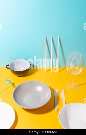 Various plates, utensils, a glass and umbrella decoration on a colorful table Stock Photo