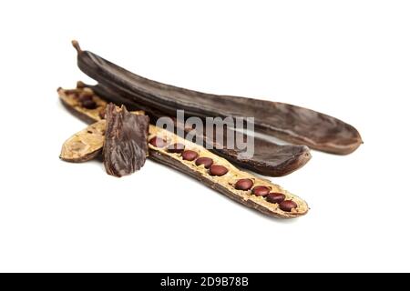 Dry carob beans with seeds isolated on white background. Healthy organic sweet vegan carob fruits. Stock Photo