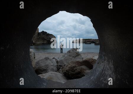 Man standing by the sea seen through a hole Stock Photo