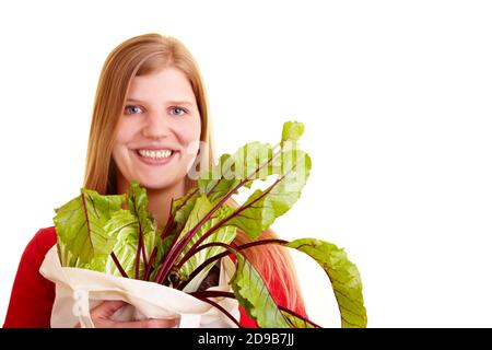 Blonde woman with beetroot (Beta vulgaris subsp. Vulgaris var. Conditiva) in shopping bag Stock Photo