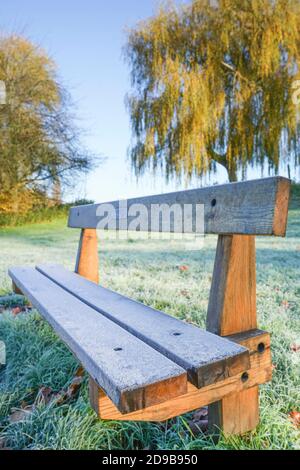 Close up of isolated memorial park bench covered in early morning, autumn frost. Stock Photo