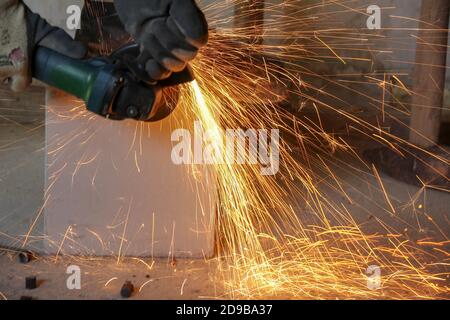 Man with a grinder working on a piece of steel Stock Photo
