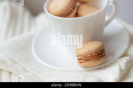 macarons in a coffee cup. caramel macaroons. Light flatley with dessert. Macaroni on white background. Cozy winter photography Stock Photo