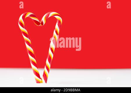 Christmas candy canes on a red background. Heart on a red background. Heart made of lollipops. Heart for valentine's day Stock Photo