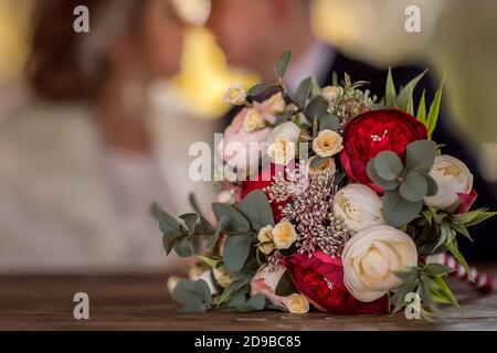 Wedding bouquet of the bride consisting of red roses, beige roses and eucalyptus leaves. Bouquet close-up. Stock Photo