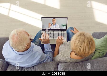 Top view of an elderly couple using a laptop for an online conference with their doctor. Stock Photo