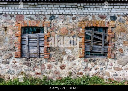 Two windows in an old building boarded up by boards Stock Photo