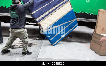 Delivery. Motion blurred image  of young man unload furniture from the truck on the streets of New York City Stock Photo