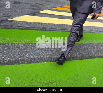 Zebra crossing. Man in a suit with a mobile phone in hand cross street at crosswalk in the city Stock Photo