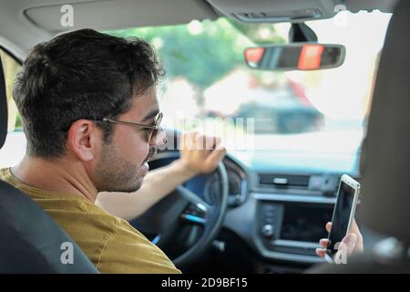 Young man unsafe driving while phone talking in front of the steering ...