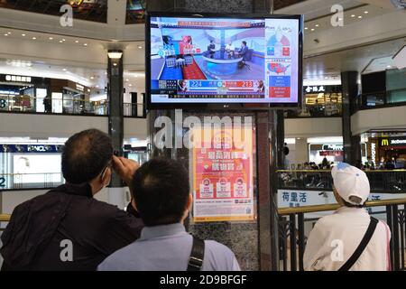 People watch live news report of the US Presidential elections at a shopping mall in Hong Kong as U.S.'s future policies on Hong Kong may be affected. Stock Photo