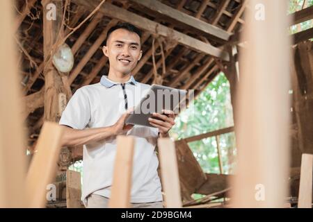 Selective focus of Asian men looking at the camera while using a tablet pc in a furniture workshop Stock Photo