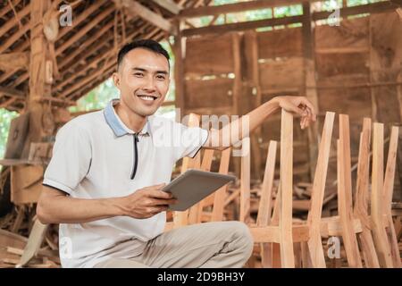 successful young entrepreneurs smile while sitting using a tablet pc in a furniture workshop Stock Photo