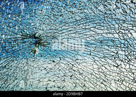 Broken window made of safety laminated glass after a stone throw, shows a characteristic circular spider web pattern and granular chunks, protection a Stock Photo