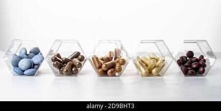 Various medical capsules and tablets in hexagonal transparent jars similar to the cell Stock Photo