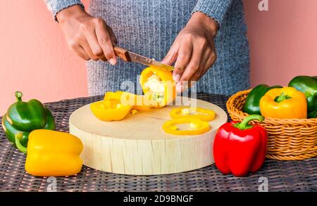 female chef cutting bell peppers on cutting board Stock Photo