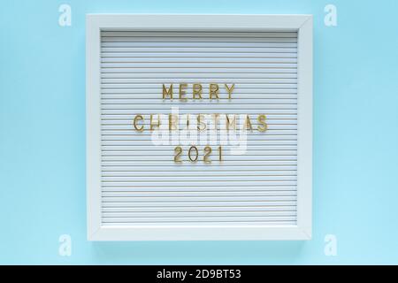Letter board with Merry Christmas 2021 greeting, decorations on blue pastel backdrop. Christmas composition. Top view Stock Photo