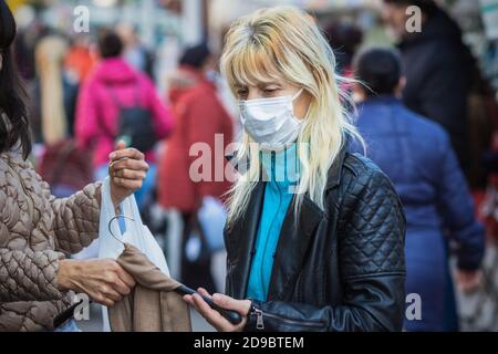 London, UK - 3 November, 2020 - A white woman wearing a face mask while shopping at Walthamstow market Stock Photo