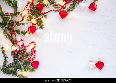 Frame made of branches of a Christmas tree and glass decorations in the shape of hearts. Stock Photo