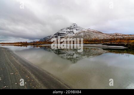 Tjahkelij mountain with snow reflecting in the Rapa river in Sarek national Park Stock Photo