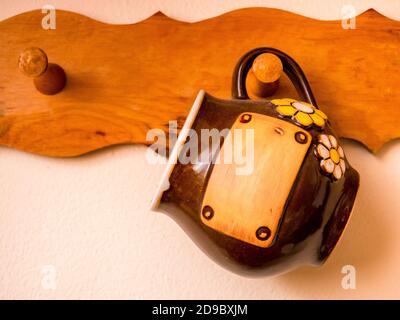 Large brown ceramic mug hanging on a wooden hanger. Concept - with an empty label. Stock Photo