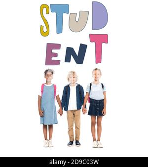 blonde schoolboy holding hands with multicultural schoolgirls near student lettering on white Stock Photo