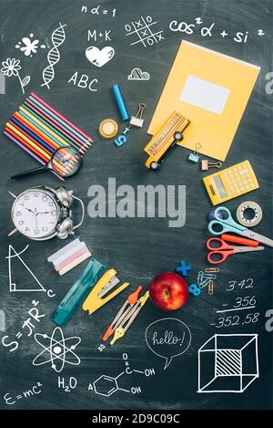 top view of frame with vintage alarm clock, green apple and school supplies on black chalkboard with illustration Stock Photo