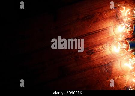 Glowing electric light bulbs laid on a rustic floor with space for copy Stock Photo
