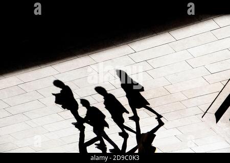 Abstract background shadow silhouette of four people walking city pavement, in high contrast  black and white Stock Photo