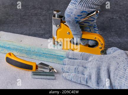 Worker performs work with a furniture stepper, shallow depth of field, close up Stock Photo