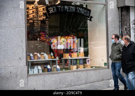 Madrid, Spain. 04th Nov, 2020. People wearing face masks to protect against the spread of coronavirus passing by a souvenir shop in Gran Via Street with the display window vandalized as riots took place the past weekend with protests against COVID-19 restrictions. Credit: Marcos del Mazo/Alamy Live News Stock Photo