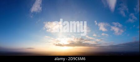 Blue sky and sunset, small clouds around the sun. Stock Photo