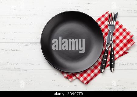 Black empty plate, fork, knife and napkin on wooden table. Top view flat lay with space for your meal Stock Photo