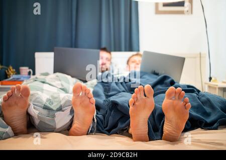 laptop, couple, woman, bed, home, man, bedroom, relationship, together, technology, computer, young, lying, people, love, wife, happy, handsome, inter Stock Photo