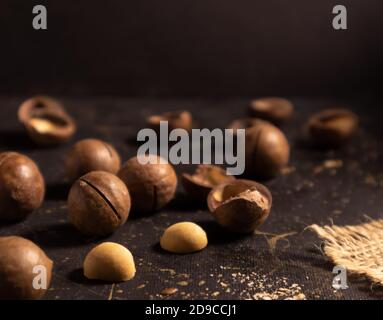 Macadamia nut in shell and peeled on a dark background. Poster, article. Stock Photo