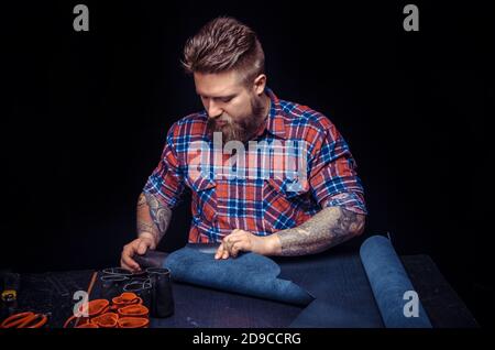 Tanner demostrating leather cutting process at his tanning shop Stock Photo